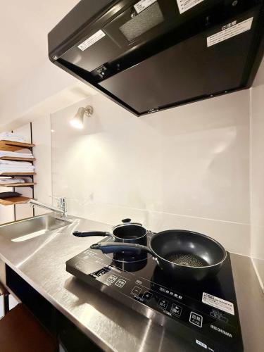 a kitchen with two pots and pans on a stove at Origaminn 401 by b hotel - 5 mins Peace Park in Hiroshima