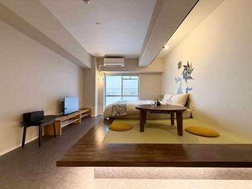 a bedroom with a bed and a table and a tv at Origaminn 303 by b hotel - 5 mins PeacePark in Hiroshima