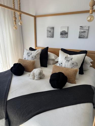 a large bed with pillows and a dog laying on it at 105 On Beach, Whale Room in St. Helena Bay