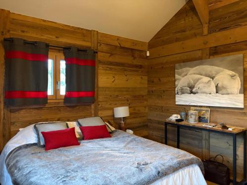 a bedroom with wooden walls and a bed with red pillows at Charmante chambre Chalet in Crozet