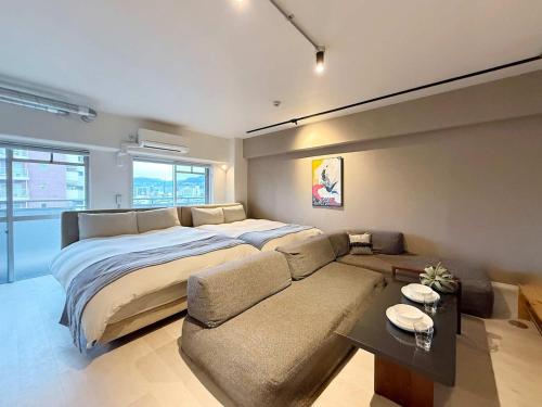 a bedroom with a large bed and a couch at Origaminn 501 by b hotel - 5 mins PeacePark in Hiroshima