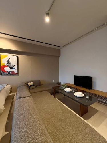 a living room with a couch and a flat screen tv at Origaminn 501 by b hotel - 5 mins PeacePark in Hiroshima