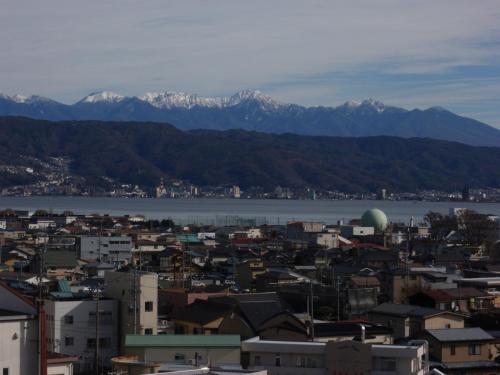 a city with snow capped mountains in the background at Hotel Crown Hills Okaya in Okaya