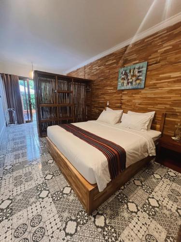 a bedroom with a large bed with a wooden wall at Sun Resort And Villa Gili Trawangan in Gili Trawangan