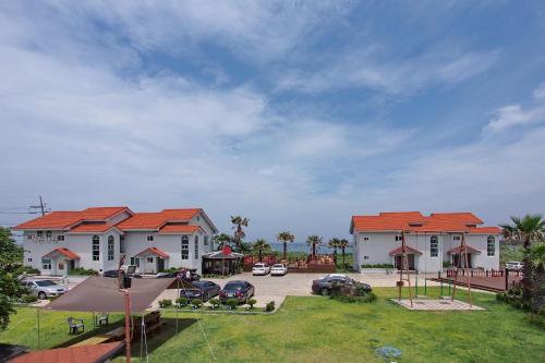 a group of houses with cars parked in a parking lot at Morning Beach Pension in Jeju