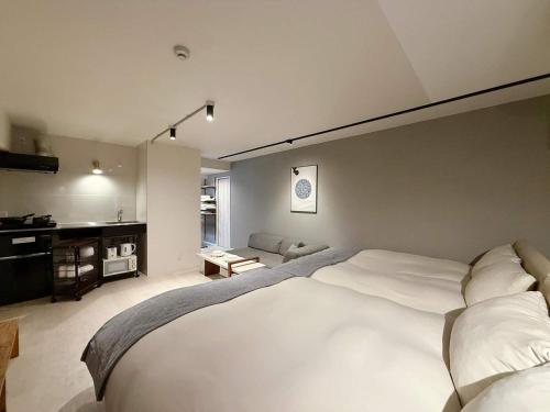 a bedroom with a large white bed and a bathroom at Origaminn 602 by b hotel - 5 mins PeacePark in Hiroshima