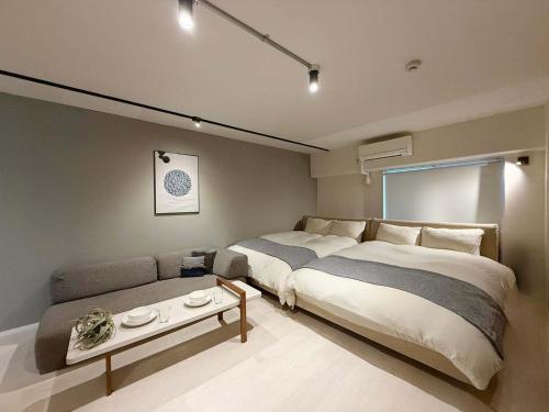 a bedroom with a large bed and a couch at Origaminn 602 by b hotel - 5 mins PeacePark in Hiroshima