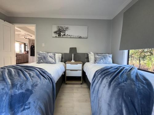 two beds sitting next to each other in a bedroom at Elephant View Homestead - Hydrangea Cottage in Plettenberg Bay
