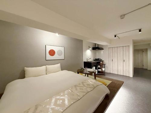 a bedroom with a large white bed and a kitchen at Origaminn 603 by b hotel - 5 mins PeacePark in Hiroshima