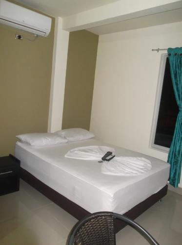 a room with a bed with a chair and a window at Hotel Monarca Putumayo in Orito