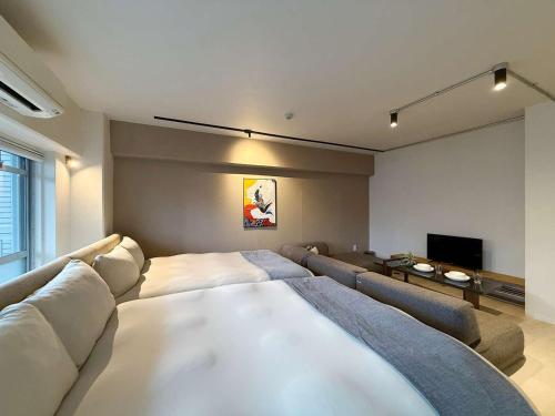 a bedroom with a large bed and a couch at Origaminn 701 by b hotel - 5 mins PeacePark in Hiroshima