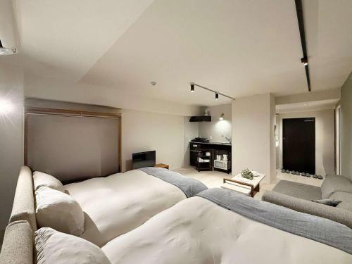 a large bedroom with two beds and a couch at Origaminn 702 by b hotel - 5 mins PeacePark in Hiroshima