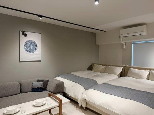 a living room with two beds and a couch at Origaminn 702 by b hotel - 5 mins PeacePark in Hiroshima