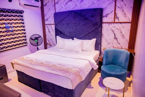 a bedroom with a bed and a blue chair at Dee Rocket Hotel & Lounge in Ibadan