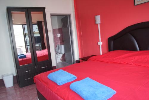 a red bedroom with two blue towels on a bed at Pineapple Guesthouse in Karon Beach