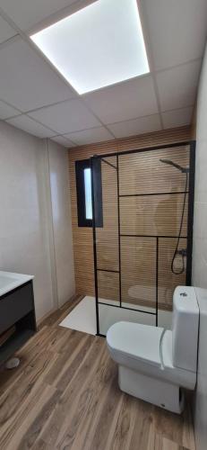 a bathroom with a toilet on a wooden floor at Enebrales Home in Punta Umbría