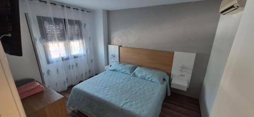 a small bedroom with a bed and a window at Enebrales Home in Punta Umbría