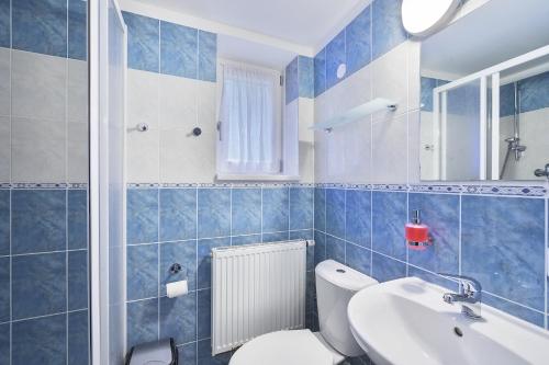 a blue tiled bathroom with a toilet and a sink at Pension Katty in Špindlerův Mlýn