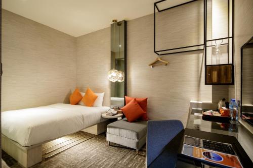 a bedroom with a bed and a chair and a table at Via Hotel Taipei Station in Taipei