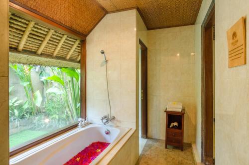 a bathroom with a bath tub and a window at Chili Ubud Cottage in Ubud