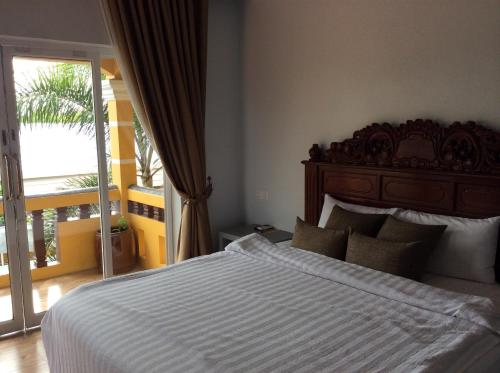 a bedroom with a large bed and a balcony at Ramchang Guesthouse in Battambang