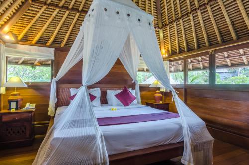 a bedroom with a canopy bed with mosquito nets at Chili Ubud Cottage in Ubud