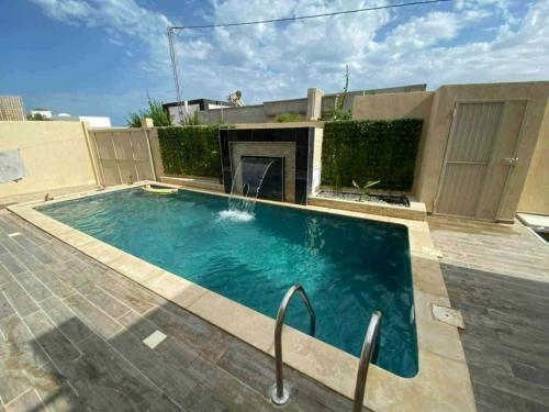 a swimming pool with a fireplace in a backyard at Villa RAZAN in Midoun