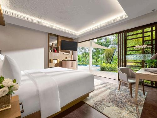 a bedroom with a large white bed and a desk at Pullman Ciawi Vimala Hills Resort in Bogor