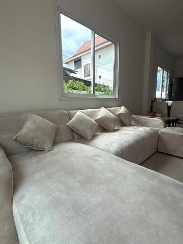 a living room with a couch and a window at Baan Thanaluk 1 Pattaya in Pattaya