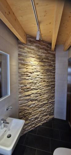 a bathroom with a sink and a stone wall at Chalet Wildi Horu OG in Niedergesteln