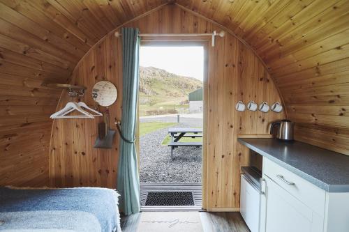 a kitchen in a wooden cabin with a door open at Iona Pods in Iona