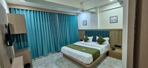 a bedroom with a bed and a blue curtain at Hotel Krishna Palace in Pālanpur