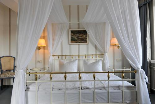 a bedroom with a canopy bed with white curtains at Wagners Hotel im Thüringer Wald in Tabarz