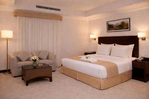 a hotel room with a large bed and a chair at Carawan Al Khaleej Hotel Olaya in Riyadh