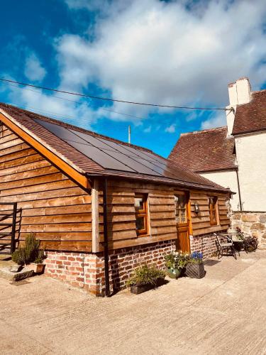 a log cabin with a solar roof on it at Enchmarsh Farm Byre in Church Stretton