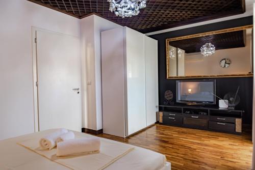 a living room with a television and a bed with towels at Central Blloku 2 bedroom Apartment in Tirana