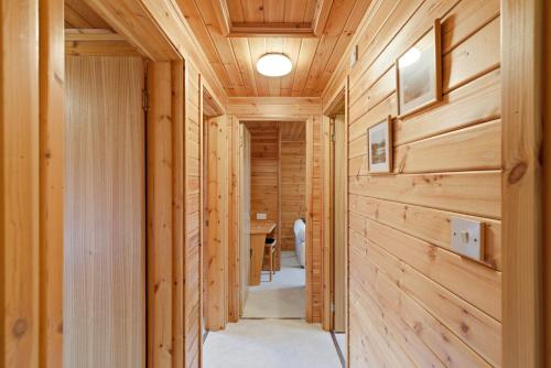 a hallway with wood paneled walls and a table at Braeknowe Scottish Cabin Getaway in Dunkeld