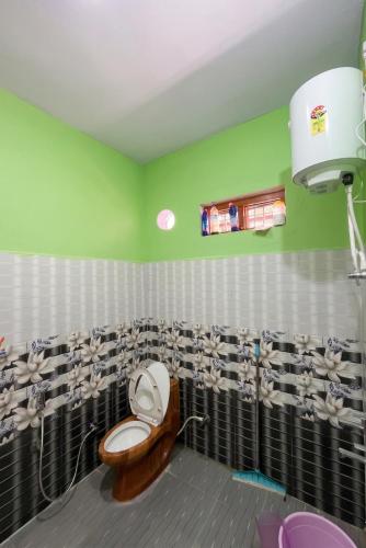 a bathroom with a toilet and a green wall at Peace Forest Retreat in Gopeshwar