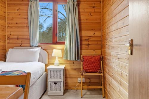 a bedroom with a bed and a window at Braeknowe Scottish Cabin Getaway in Dunkeld