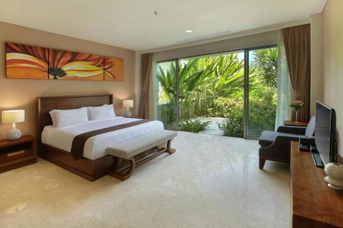 a bedroom with a bed and a tv and a balcony at Luxury Apartment at AYANA Residences in Jimbaran