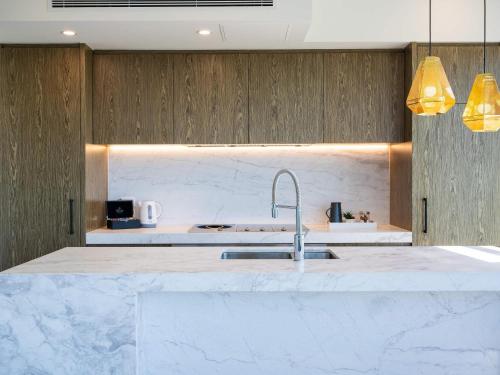 a kitchen with white marble countertops and a sink at The Sebel Melbourne Malvern in Melbourne