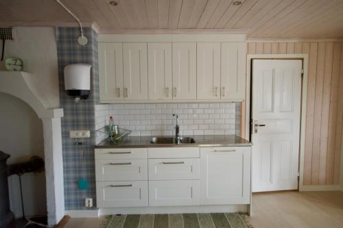a kitchen with white cabinets and a sink at Hagabergets Vandrarhem in Ullared