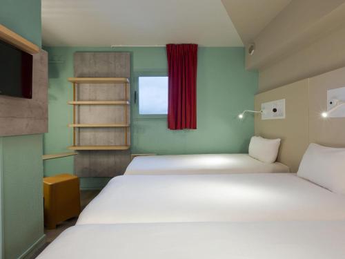 a small room with two beds and a window at ibis budget Chilly-Mazarin Les Champarts in Chilly-Mazarin