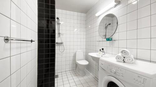 a white tiled bathroom with a toilet and a sink at Bergvegen Guesthouse Aalesund in Ålesund