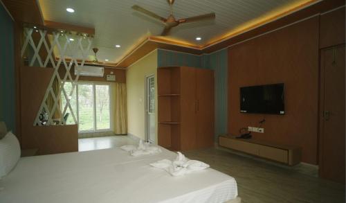 a bedroom with a bed and a flat screen tv at Siddharaj Resort in Mal bazar