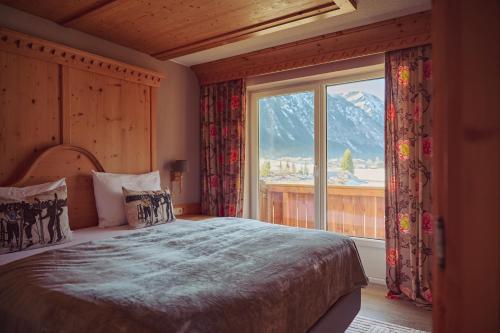 ein Schlafzimmer mit einem Bett und einem großen Fenster in der Unterkunft Hotel Hohenfels in Tannheim