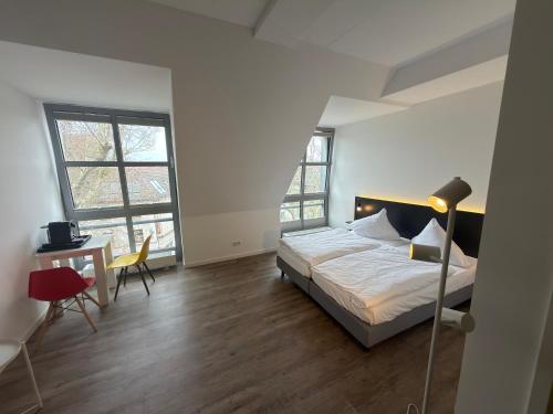 a bedroom with a bed and a desk and windows at Printhouse in Münster
