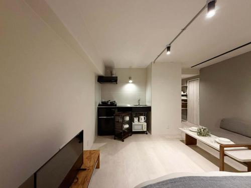 a room with a bed and a couch and a television at Origaminn 502 by b hotel - 5 mins PeacePark in Hiroshima
