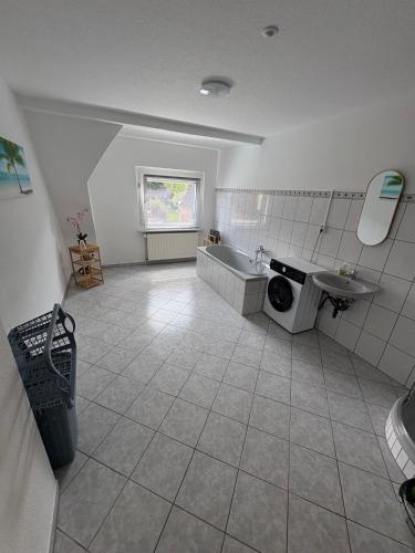 a bathroom with a tub and a sink and a washing machine at Ferienwohnung Emma in Marl