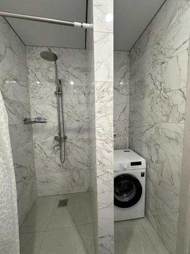 a bathroom with a shower and a washing machine at Welcome Hotel in Kostanay
